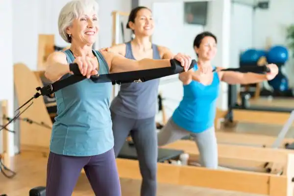 Toning Arms After 60: Empowering Womens Fitness Through Effective Weight Training 2 older woman doing weight training West Drayton and resistance in the gym to tone upper arms